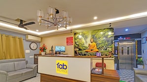 Un espace d’accueil d’hôtel avec une statue de Bouddha, une horloge et un écran de télévision.