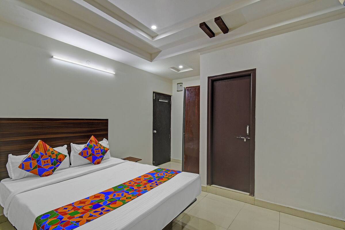 Habitación de hotel con cama, dos puertas e iluminación empotrada en el techo.