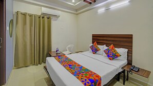 Une chambre d’hôtel équipée d’un lit, d’une table de chevet avec un téléphone, d’un miroir et d’un appareil de climatisation.