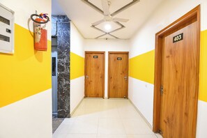 Un pasillo con dos puertas de madera, identificadas con los números 401 y 402, un ventilador de techo y un extintor en la pared izquierda.