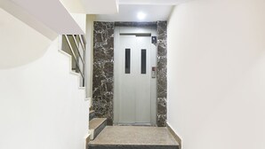 Un escalier étroit menant à une porte dotée d’une serrure électronique, flanquée de murs blancs et agrémentée de touches de marbre.