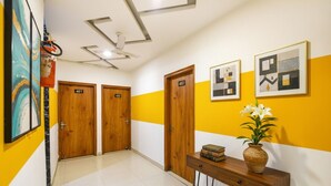 Un couloir avec des portes en bois numérotées 401 et 402, une console sur laquelle sont posés un vase et des livres, et des œuvres d’art encadrées accrochées au mur.