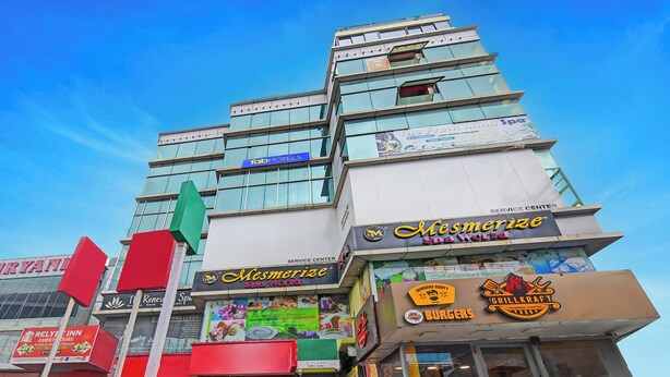 Un immeuble à plusieurs étages abritant divers commerces, notamment un spa, un restaurant-grill et un centre de services.