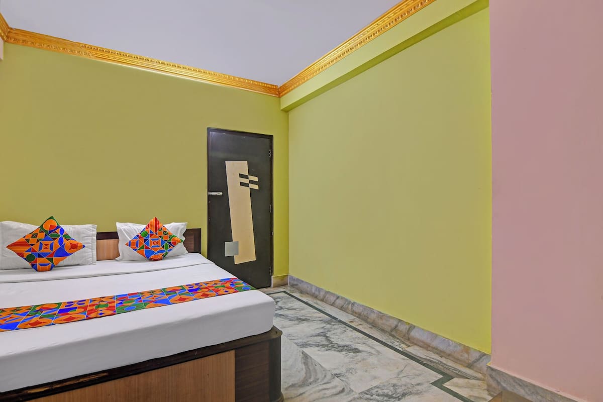 A hotel room with a bed, pillows, a door, and a tiled floor.