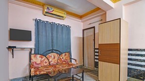 Une chambre avec un lit, une armoire, un bureau avec une chaise, une télévision et un rideau.