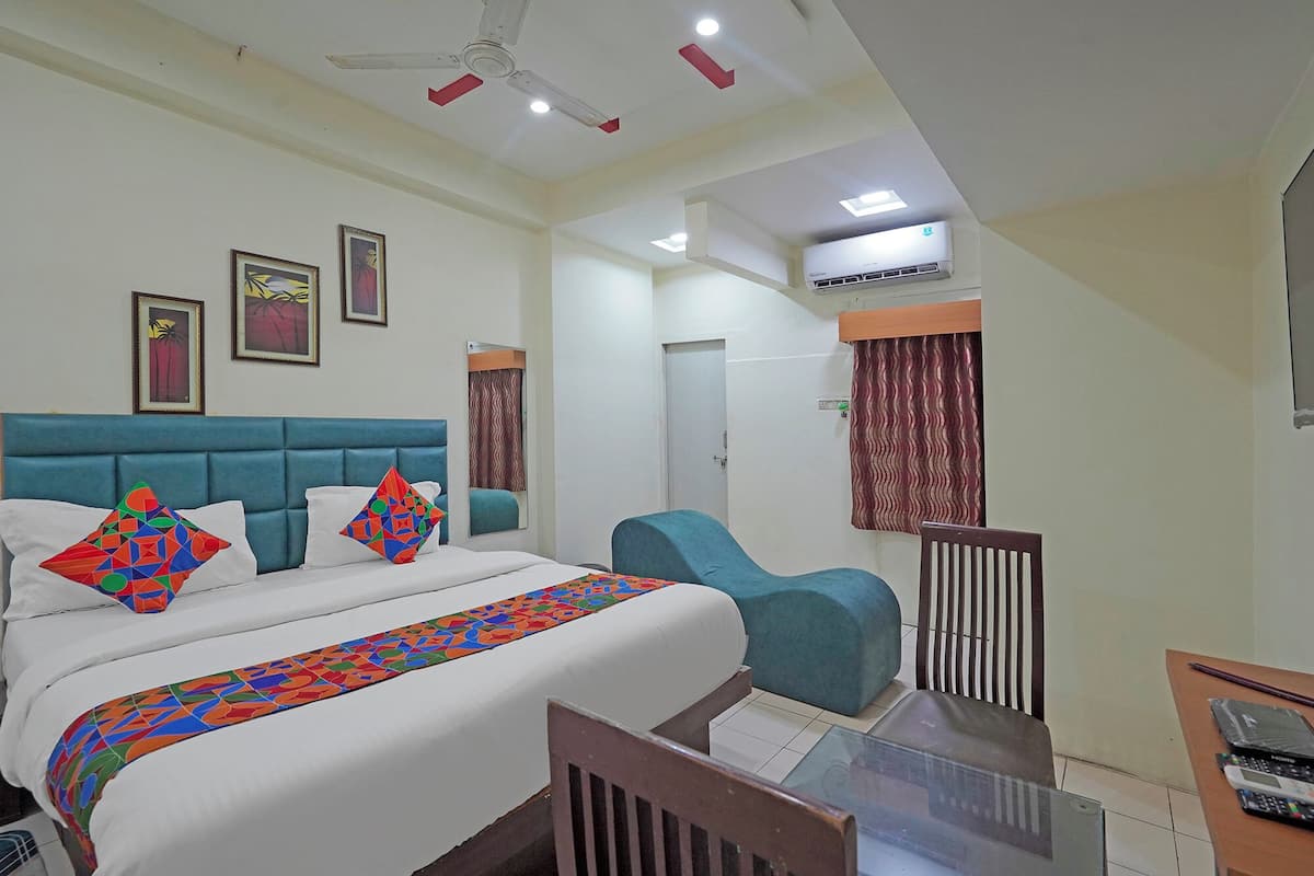 Une chambre d’hôtel équipée d’un lit, d’un bureau, d’une chaise, d’un ventilateur de plafond et d’un appareil de climatisation.