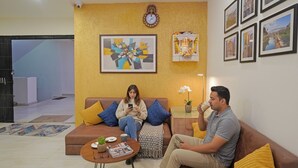 A living room with a sofa, coffee table, and a wall with framed pictures. - Fabhotel Rajtilak (Ahmedabad)