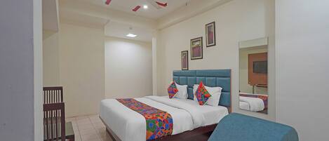 A hotel room with a bed, a chair, a ceiling fan, and a mirror.