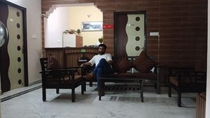 A man sitting on a couch in a lobby with wooden walls and a tiled floor. - Fabhotel Crown Inn (Lucknow)
