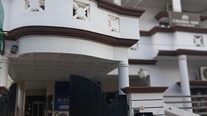 A white building with a curved balcony and decorative cutouts. - Fabhotel Crown Inn (Lucknow)
