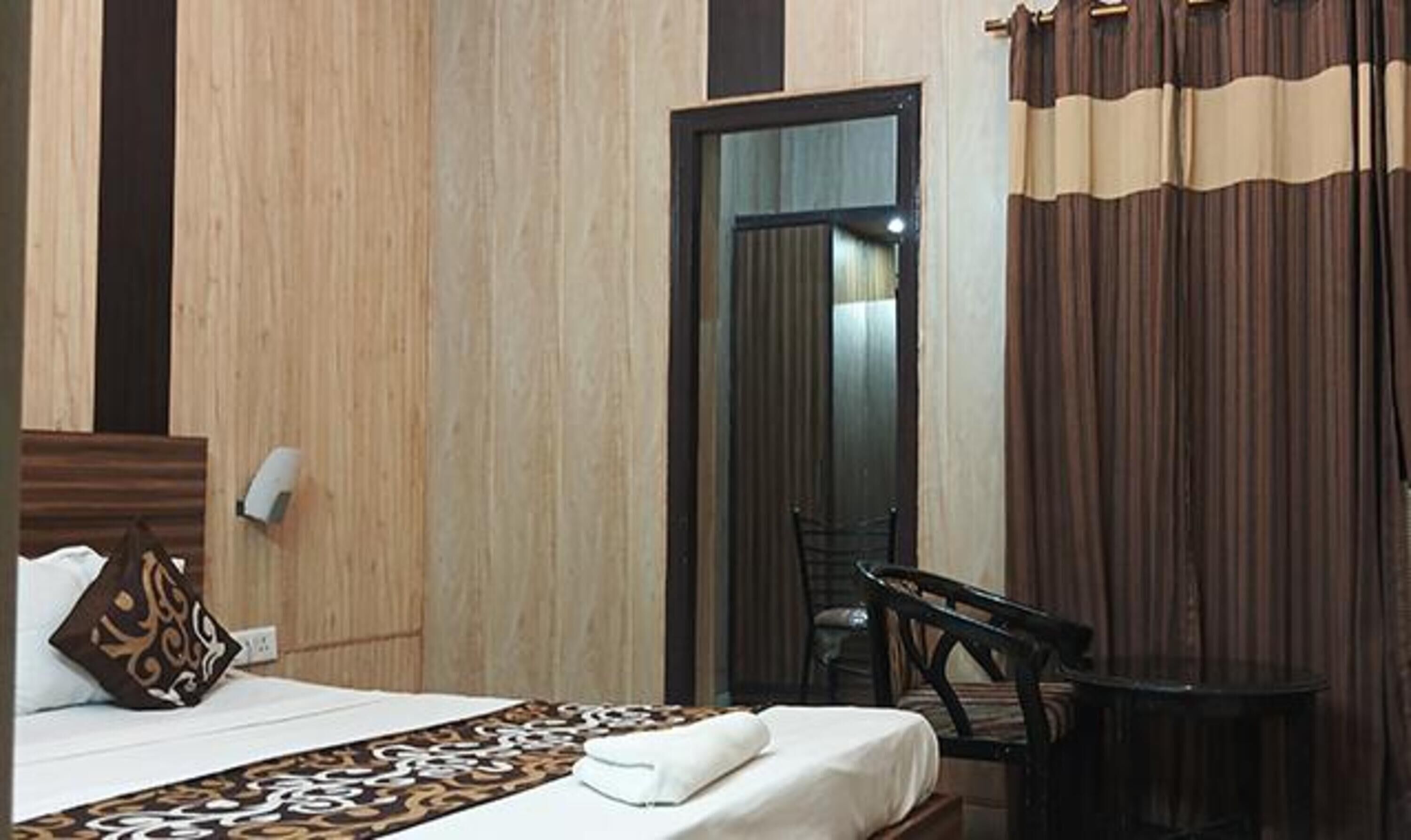 Una habitación de hotel con cama, una silla, una mesita y un espejo.
