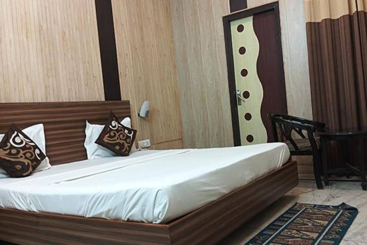 A neatly made bed with a wooden headboard, a small bedside table, and a chair.
