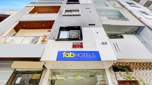 En hög byggnad med flera våningar, utmärkt av en stor skylt med texten ”fabHOTELS”.
