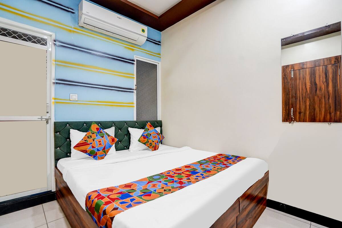 A hotel room with a bed, a window, and a wooden wardrobe.