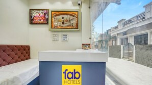 En receptionsdisk med varumärket ”fab hotels”, en vadderad bänk och två inramade konstverk på väggen.