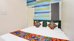 Ett hotellrum med en säng, en luftkonditionering, ett fönster och en dörr.