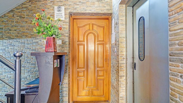 A wooden door with a sign above it, a potted plant, and a metal railing. - Fabhotel Blue Moon Residency (Chennai)