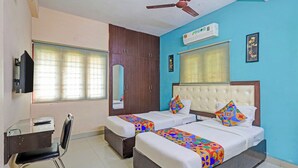 A hotel room with two beds, a desk, a chair, a ceiling fan, and an air conditioning unit. - Fabhotel Blue Moon Residency (Chennai)