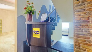 A hotel reception desk with a 'fab hotels' sign, a vase with flowers, and a staircase in the background. - Fabhotel Blue Moon Residency (Chennai)