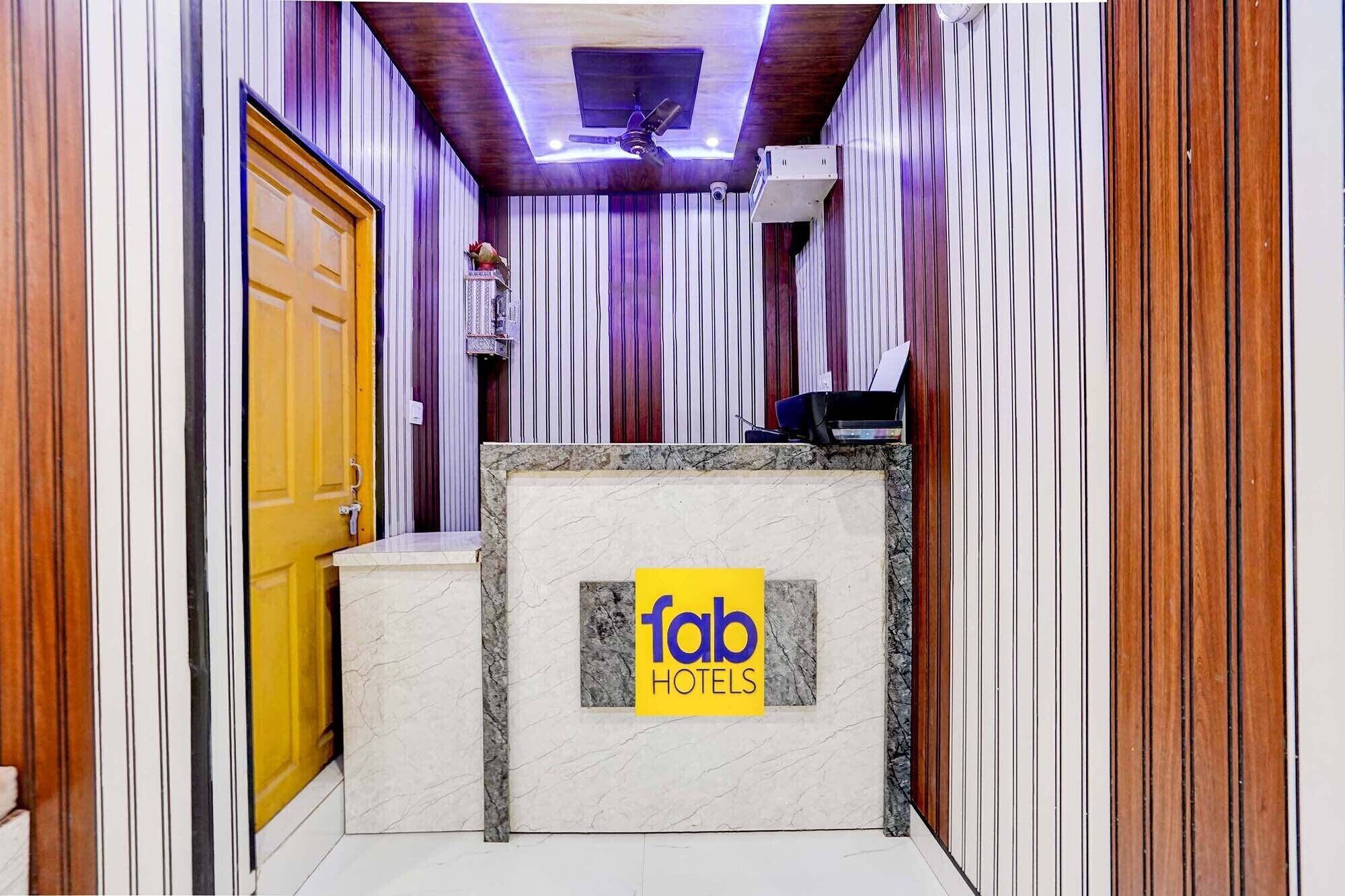 A hotel reception area with a marble counter, a ceiling fan, and vertical wooden paneling.