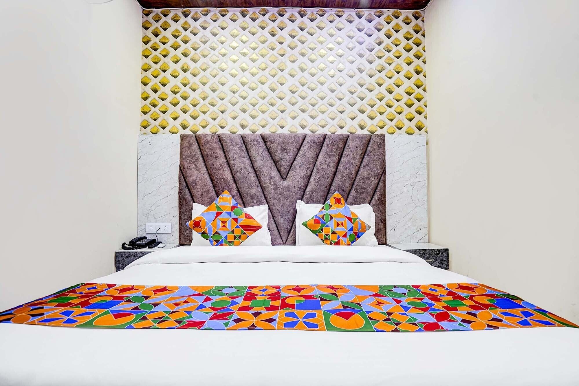 A bed with a colorful geometric-patterned bedspread, a headboard with a diamond-patterned panel, and two decorative pillows with geometric designs.