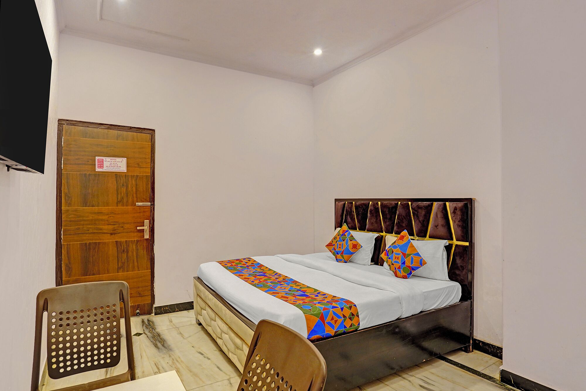 A bedroom with a bed, a wooden door, a chair, and a small table.