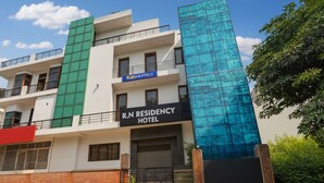 A multi-story hotel with a modern facade, including a prominent glass section. - Fabhotel Rn Residency (Ghaziabad)