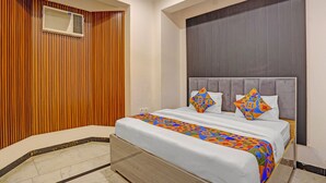 A hotel room with a bed, a wooden panel wall, a large window, and a ceiling vent. - Fabhotel Rn Residency (Ghaziabad)