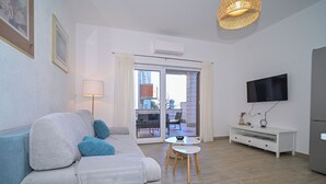 A modern living room with a sofa, a coffee table, and a TV. - AMI Apartment Strožanac (Podstrana)