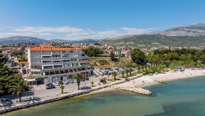 A coastal hotel with multiple floors, a beach, and a mountainous backdrop. - AMI Apartment Strožanac (Podstrana)