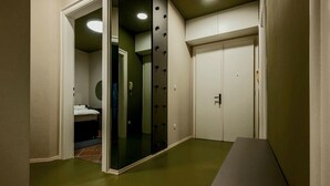A hallway with a mirrored closet door, a bench, and a door with a handle.