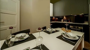 A modern kitchen with dark cabinets, a white countertop, and a dining area with a white table set for four.