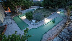 A miniature golf course with multiple green putting areas, surrounded by gravel and small plants. - Hill Pool House, Kaštel Kambelovac Retreat (Kaštel Kambelovac)