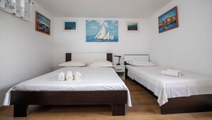 A hotel room with a large bed, two smaller beds, a nightstand, and a painting of sailboats on the wall. - Hill Pool House, Kaštel Kambelovac Retreat (Kaštel Kambelovac)