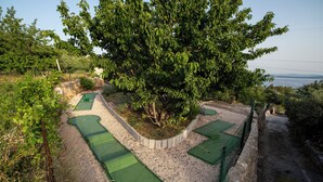 A golf course with multiple green mats and a large tree in the center. - Hill Pool House, Kaštel Kambelovac Retreat (Kaštel Kambelovac)