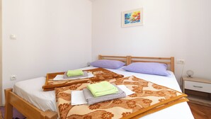 A bedroom with two beds, each with a patterned bedspread, pillows, and folded towels. - Kira, One Bedroom Apartment In Old Town (Split)