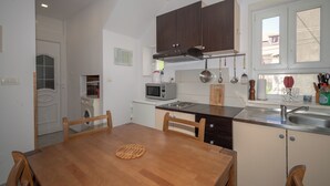 A compact kitchen with wooden cabinets, a microwave, and a sink. - Kira, One Bedroom Apartment In Old Town (Split)