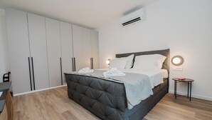 Egy modern hálószoba, amelyben egy nagy ágy, egy szekrény és egy légkondicionáló található.