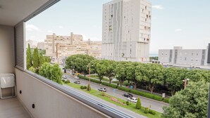 Egy erkély, ahonnan a városra nyílik kilátás, beleértve egy magas épületet és egy autókkal közlekedő utat.