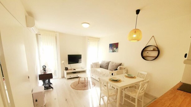 A modern living room with a sofa, dining table, and chairs. There is a television and a small table with decorative items. - Koko&Friends, Charming Place In Quite Neighborhood (Split)
