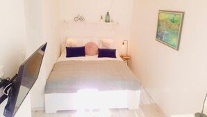 A bedroom with a bed, a nightstand, a lamp, a painting, and a bicycle on the wall. - Koko&Friends, Charming Place In Quite Neighborhood (Split)