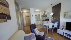 Een moderne woonkamer met een bank, een eethoek en een keuken op de achtergrond.