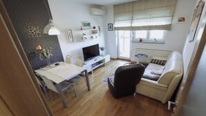 Een moderne woonkamer met een bank, televisie, eettafel en decoratieve objecten.