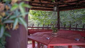 Un pavillon en bois, doté d’une table et de bancs, entouré de verdure.
