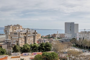 A coastal cityscape with multi-story buildings, a prominent church, and a view of the sea. - Vuvuzela Bay, Three-Bedroom Apartment (Split)
