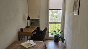A small, well-lit room with a bed, a desk, a chair, and a potted plant. - Vuvuzela Bay, Three-Bedroom Apartment (Split)