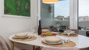 A dining table set with plates, glasses, and a bottle of wine, with a city view through large windows. - Zozo, Modern Two-Bedroom Suite (Split)