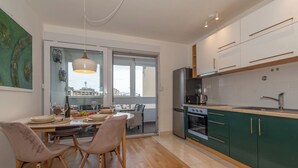 A modern kitchen with wooden flooring, a dining area with a table and chairs, and a view through a glass door. - Zozo, Modern Two-Bedroom Suite (Split)