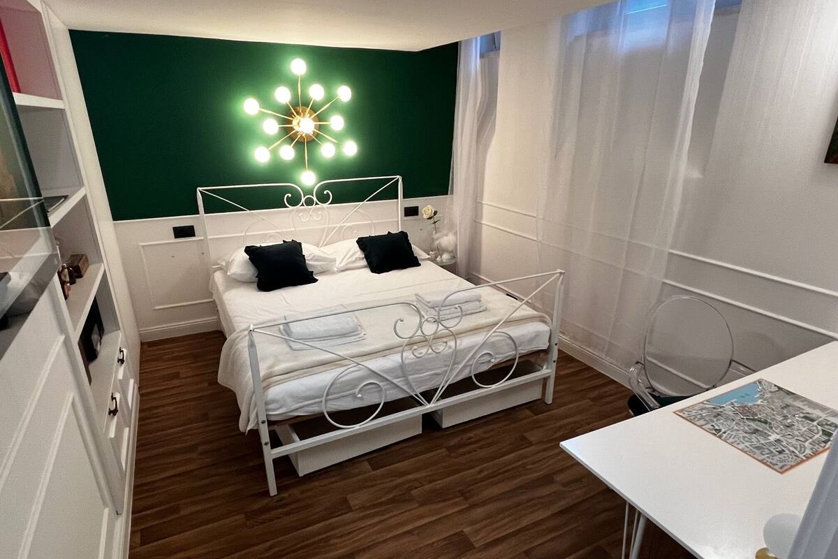 A neatly arranged bedroom with a bed, bedside table, and a wall-mounted light fixture.