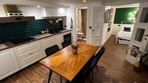 Een moderne keuken met witte kastjes, een houten eettafel en zwarte stoelen. Op de tafel staat een kleine plant.